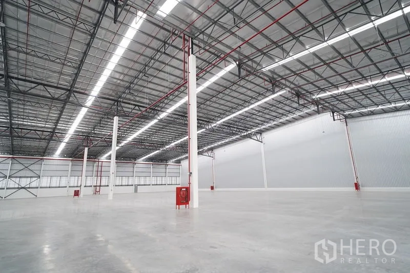 Warehouse for rent in Khlong Luang, Pathum Thani - Warehouse bay with red fire hose reels, clear-span layout, and steel roof structure.