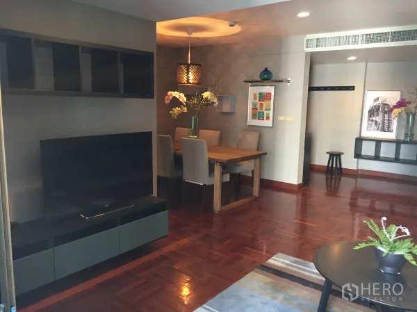 Condominium for rent in Pathum Wan, Bangkok - Open-plan living and dining area with TV console, wooden floors, and a dining table in a Bangkok condo.