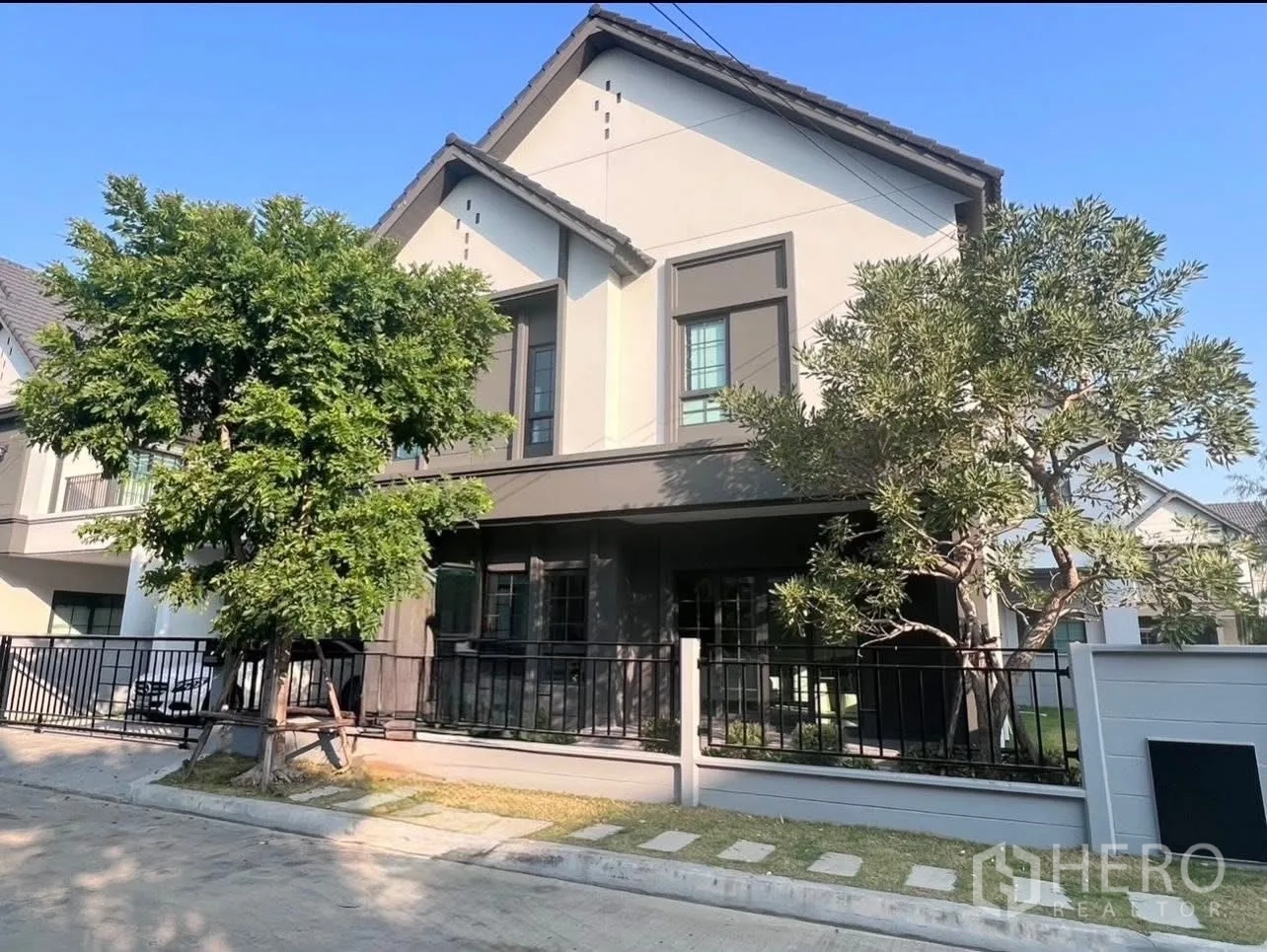 独立式住宅 出租在Bang Phli, Samut Prakan - 现代两层独栋外观，双坡屋顶、围栏与成树。