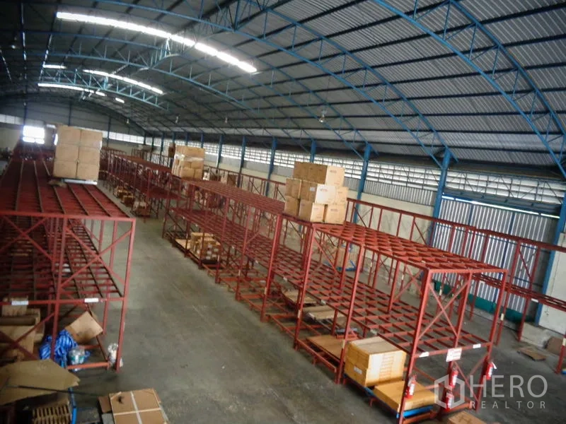 货栈 出租或出售在Lat Lum Kaeo, Pathum Thani - 俯拍仓库通道，顶层货架放置纸箱与宽阔地面空间。