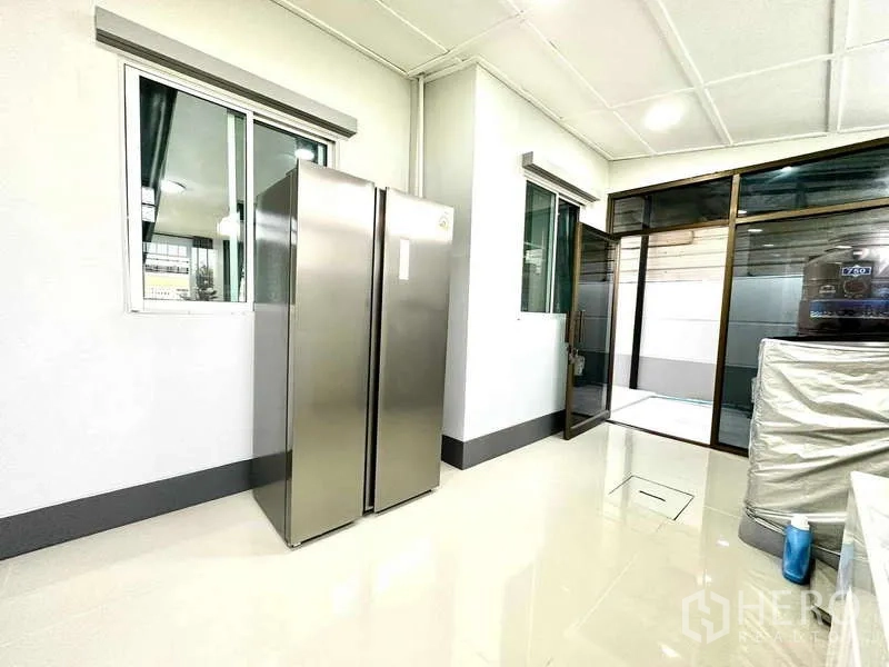 Detached House for rent in Lat Krabang, Bangkok - Kitchen view with side-by-side fridge and door to outdoor area.