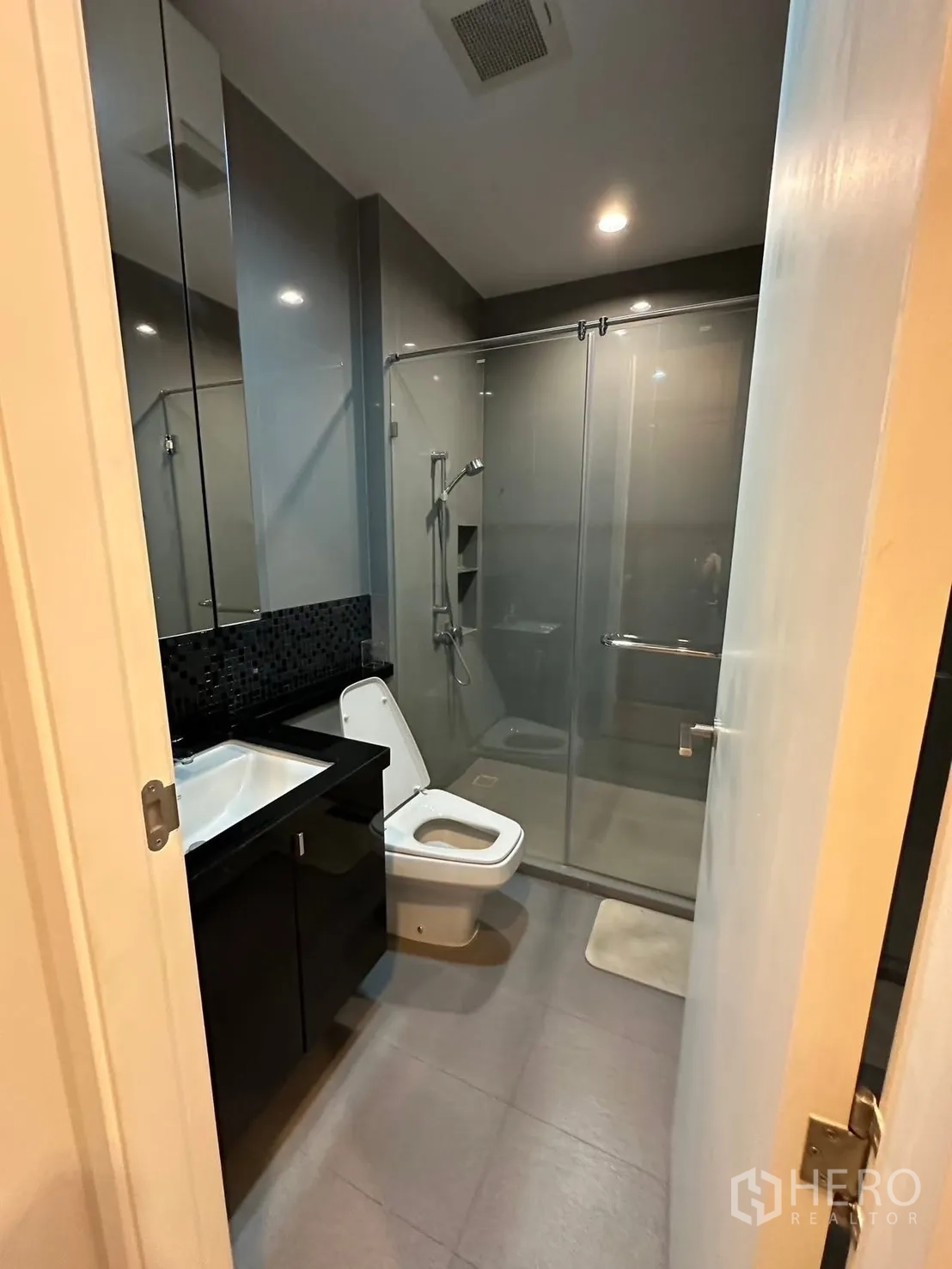 Condominium for rent or sale in Chatuchak, Bangkok - Modern bathroom with glass-enclosed shower, vanity, and toilet.