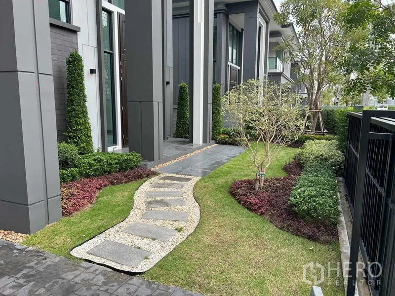 独立式住宅 出租在Khlong Sam Wa, Bangkok - 侧院景观花园，曲线踏步石小径，修剪整齐的灌木与立柱。
