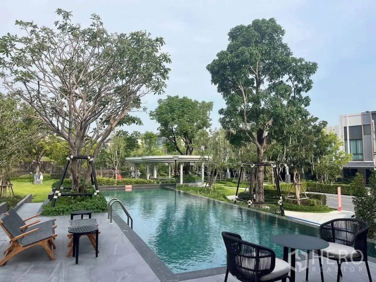 ทาวน์เฮาส์ for rent in Bang Phli, Samut Prakan - สระว่ายน้ำล้อมด้วยต้นไม้ใหญ่ เก้าอี้พักผ่อน และทางเดินสวน