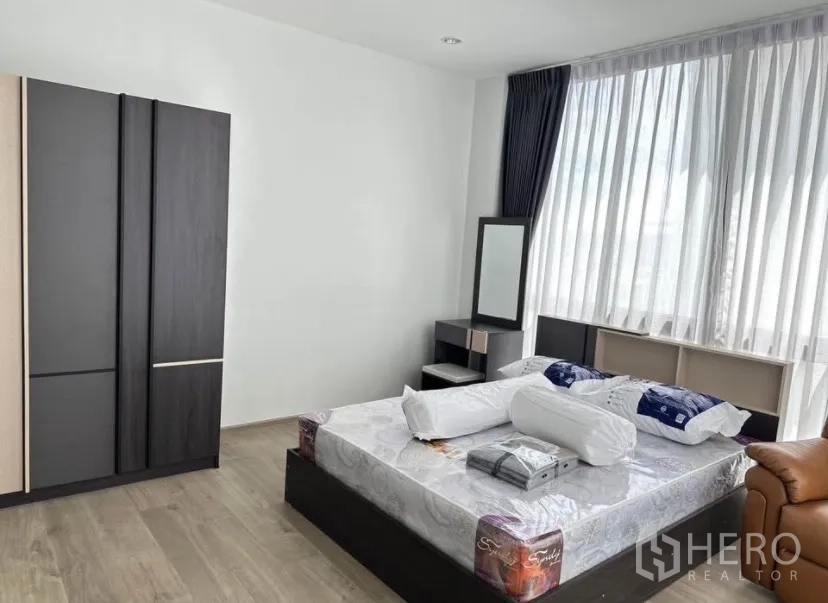 Detached House for rent or sale in Lat Krabang, Bangkok - Spacious bedroom with large windows, wood flooring and a dark wardrobe
