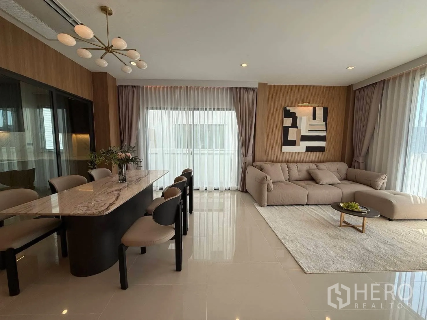 独栋房屋 for rent in Bang Phli, Samut Prakan - 开放式客餐厅，岩板餐桌、吊灯、L型沙发与落地窗。