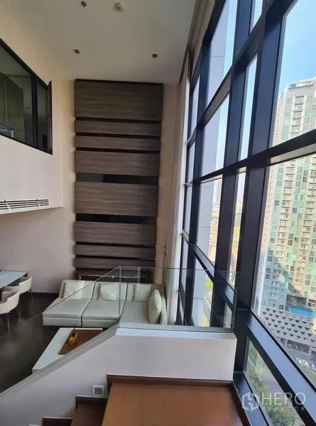 公寓 出租或出售在Huai Khwang, Bangkok - 楼梯与整面落地玻璃并行，俯瞰城市天际线。