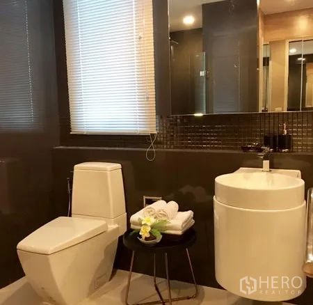 Condominium for rent in Khlong Toei, Bangkok - Second bathroom featuring toilet, circular basin, wall mirror and window blinds.