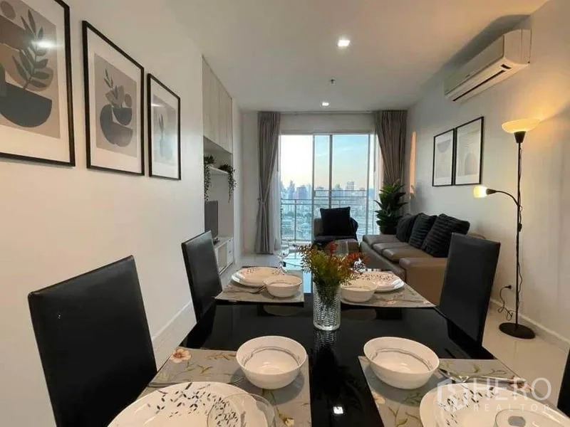 คอนโด ให้เช่าหรือขายในWatthana, Bangkok - โต๊ะอาหารจัดชุดพร้อมมุมมองไปยังโซนรับแขกและวิวเมืองผ่านระเบียง