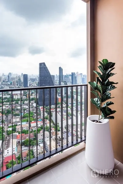 公寓 出租在Khlong Toei, Bangkok - 阳台栏杆与绿植，俯瞰曼谷城市天际线。