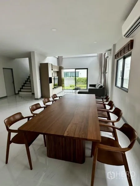 Detached House for rent in Bang Phli, Samut Prakan - Open-plan dining near the staircase with wood table and eight matching chairs.
