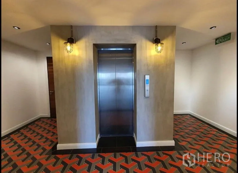 Condominium for rent in Watthana, Bangkok - Elevator landing with warm lighting and red-and-black patterned floor tiles.