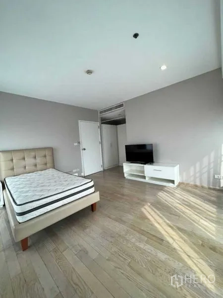 Condominium for rent in Khlong Toei, Bangkok - Spacious master bedroom with wood flooring and abundant natural light from two sides.