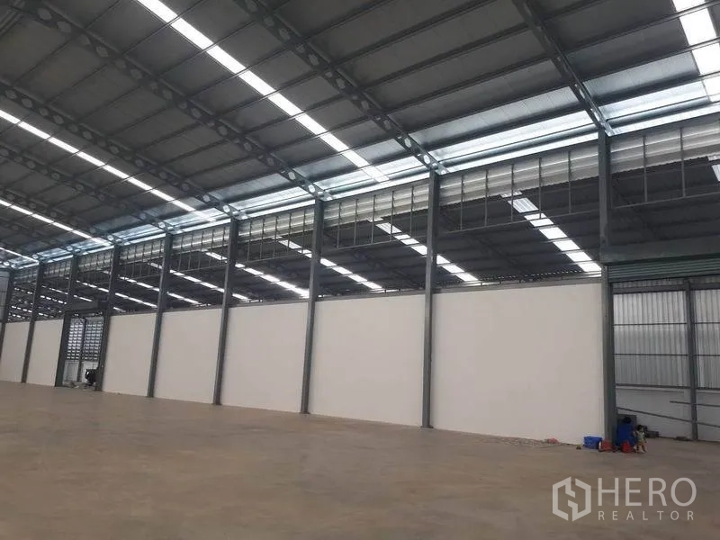 Warehouse for rent in Bang Phli, Samut Prakan - Open-plan storage hall with white partition wall, skylights and smooth concrete slab.
