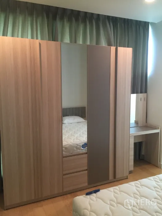 Condominium for rent in Bang Kho Laem, Bangkok - Built-in wooden wardrobe with mirror and a dressing table beside the window.