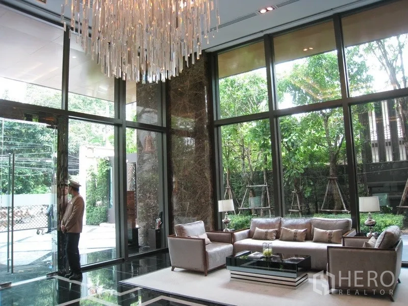 公寓 出租在Watthana, Bangkok - 优雅大堂休息区，挑高吊灯与落地窗，园景环绕。
