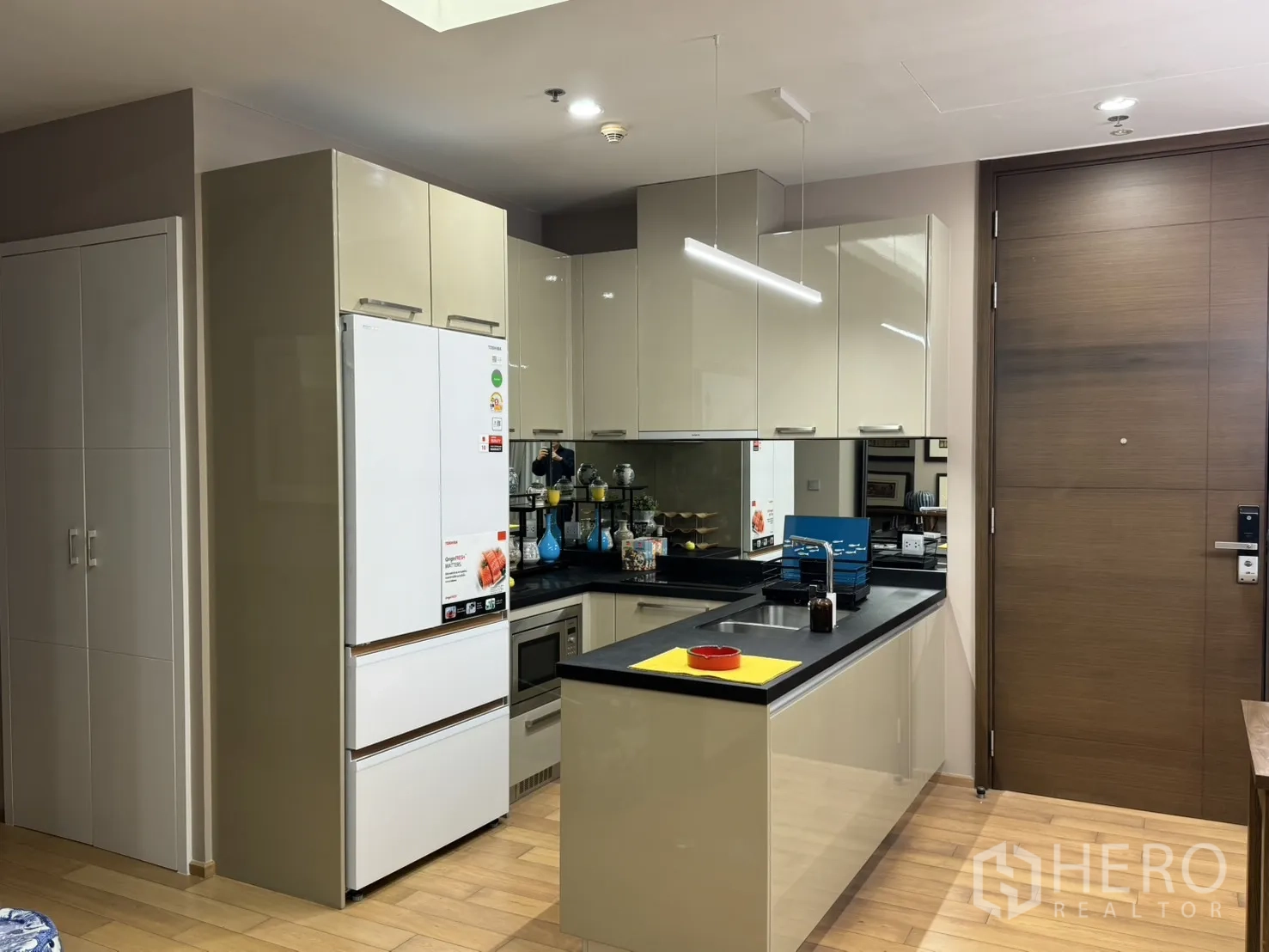 公寓 for rent in Watthana, Bangkok - 现代厨房配高光柜体、白色冰箱与黑色台面。