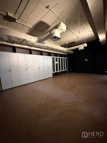 办公空间 出租在Watthana, Bangkok - 独立办公室，木地板、整排白色储物柜与深色墙面。