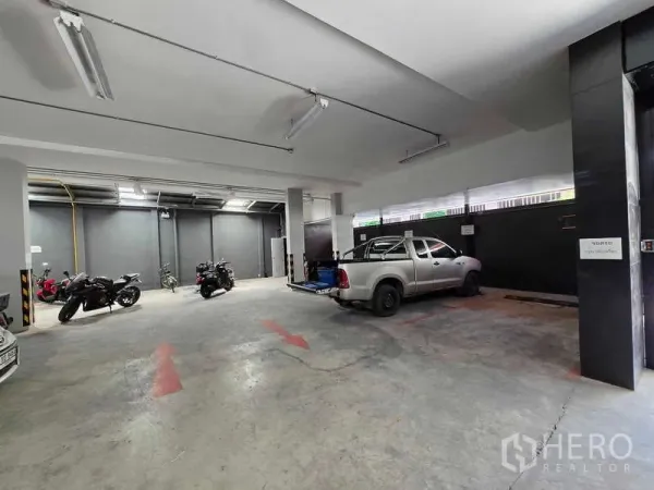 Retail Space for rent in Khlong Toei, Bangkok - Spacious indoor parking bay with fluorescent lighting and a wide entrance, ideal for retail loading access.