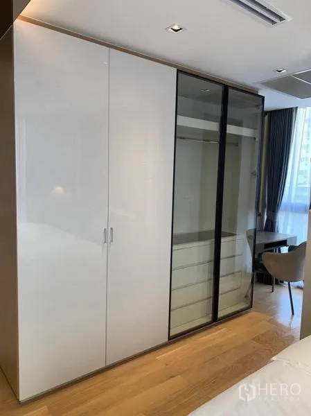 公寓 出租在Watthana, Bangkok - 主卧衣柜，白色亮面与玻璃推拉门。