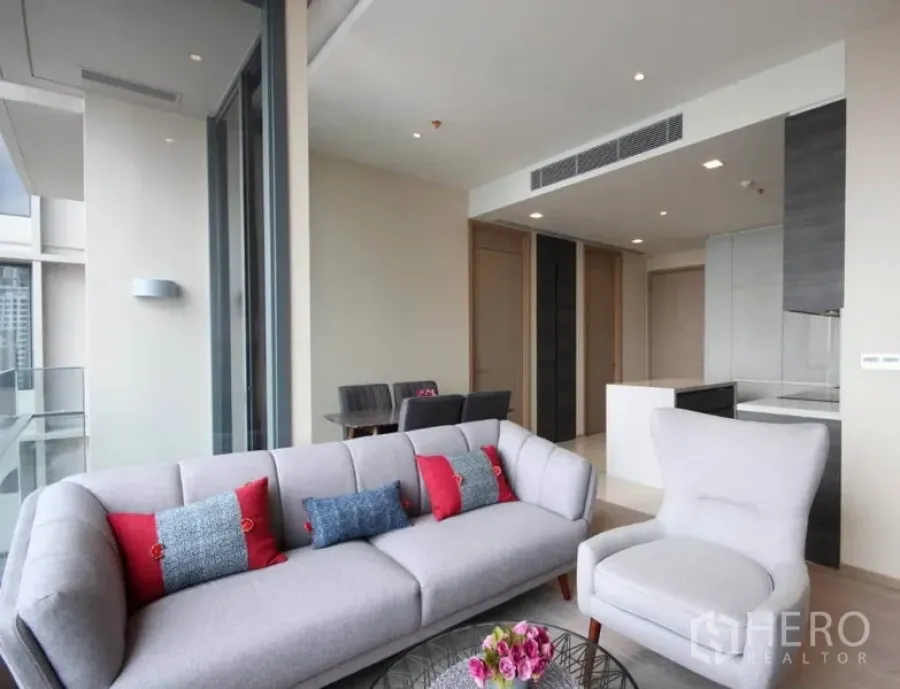 公寓 出租在Watthana, Bangkok - 客厅配柔软沙发与扶手椅，连接阳台与天际线景观。