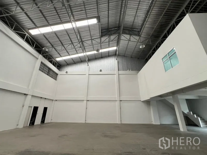 Warehouse for rent in Phra Samut Chedi, Samut Prakan - Open warehouse with mezzanine office on the right and a high-clearance ceiling.