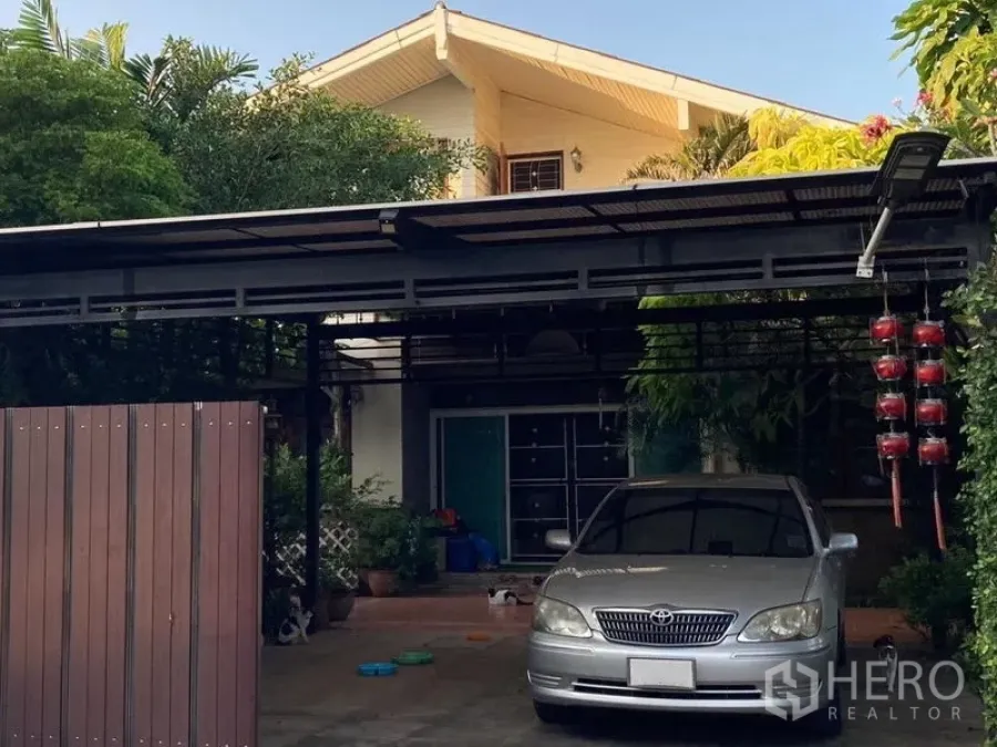 Detached House for sale in Wang Thonglang, Bangkok - Front facade with covered parking area and greenery surrounding the detached house.