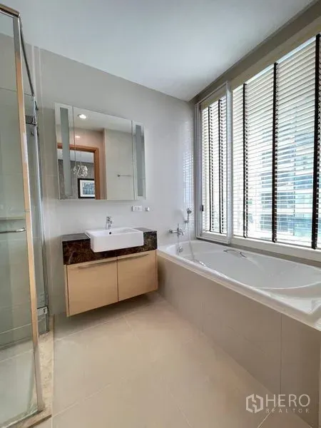 Condominium for rent in Watthana, Bangkok - Bathroom featuring a soaking tub by a large window, vanity and blinds.