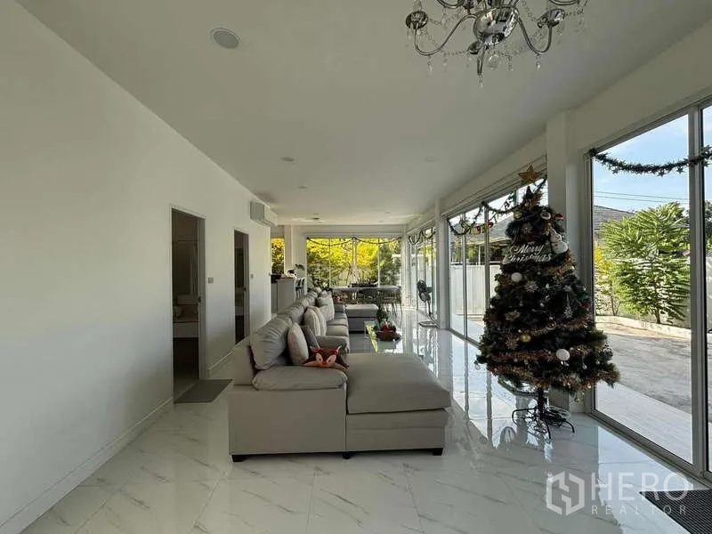 Detached House for rent in Lat Krabang, Bangkok - Spacious living room decorated for Christmas with chandelier and floor‑to‑ceiling glass.