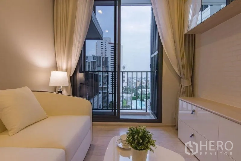 Condominium for sale in Watthana, Bangkok - Living room with TV cabinet and sliding doors to a balcony overlooking the city.