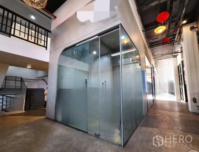 零售空间 for rent in Sathon, Bangkok - 走廊拐角处的玻璃橱窗铺，采光良好，外露天花灯具，旁有楼梯与夹层。