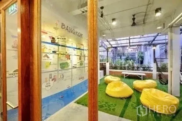 店屋 出租在Pathum Wan, Bangkok - 玻璃围合的休闲区，通向带顶露台，草坪上设有懒人沙发。