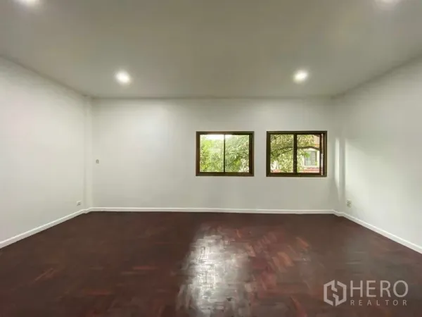 带办公室的家 出租或出售在Suan Luang, Bangkok - 明亮的室内空间，嵌灯、两扇窗与深色人字拼木地板。