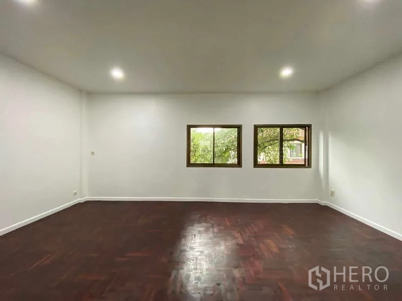 带办公室的家 出租或出售在Suan Luang, Bangkok - 明亮的室内空间，嵌灯、两扇窗与深色人字拼木地板。