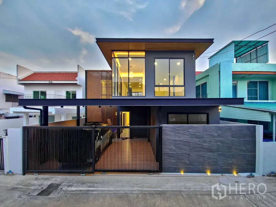 独立式住宅 出售在Khlong Toei, Bangkok - 黄昏时的现代两层独栋外立面，带围栏车位与大窗。