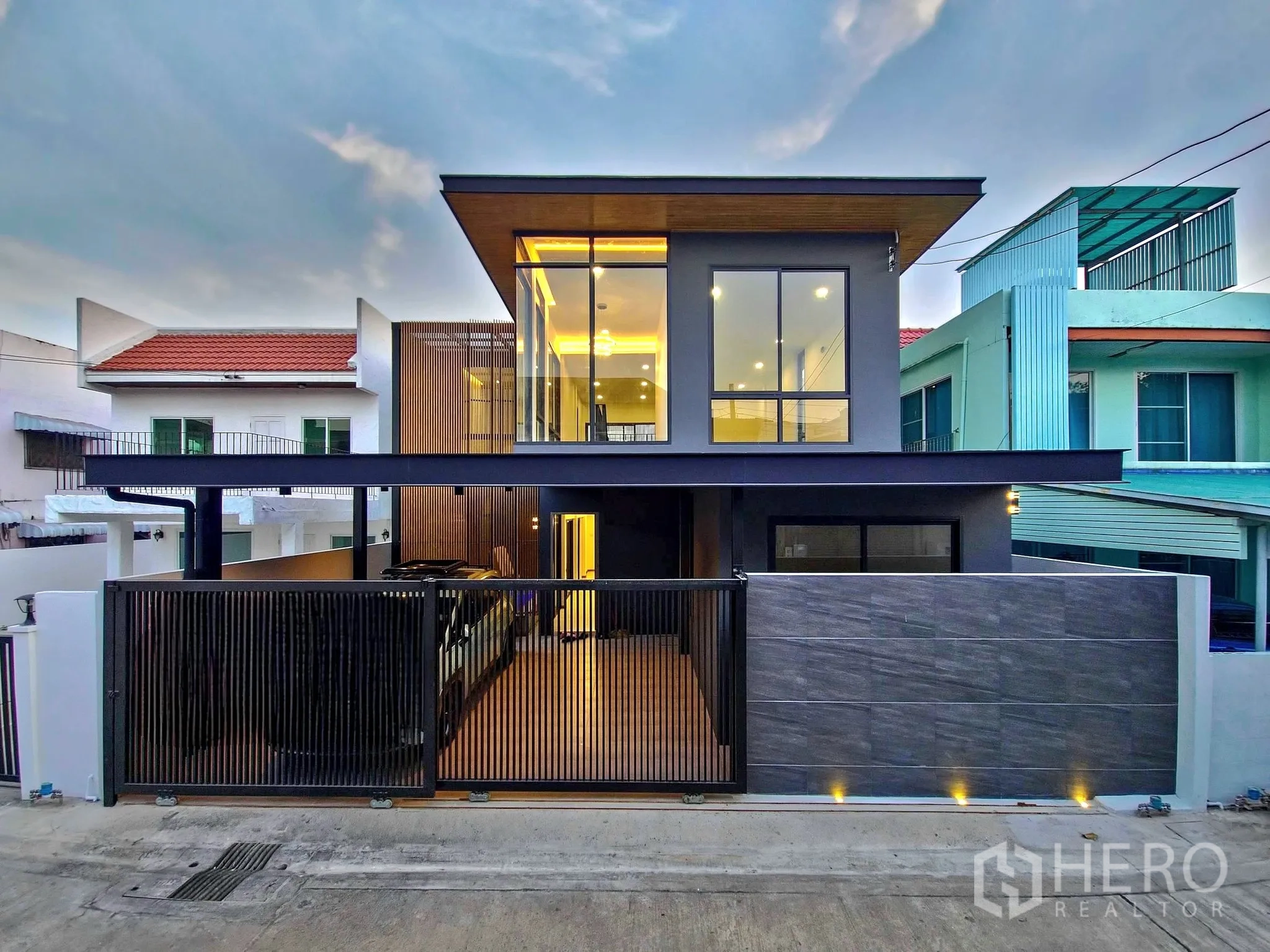 独立式住宅 出售在Khlong Toei, Bangkok - 黄昏时的现代两层独栋外立面，带围栏车位与大窗。