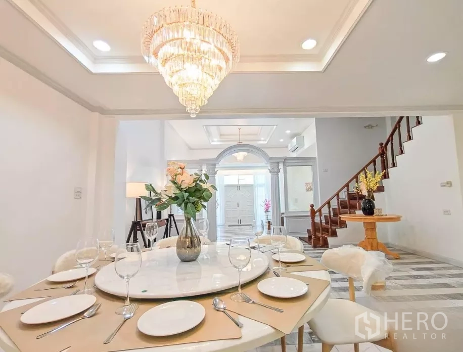Detached House for rent in Yan Nawa, Bangkok - Dining area looking toward the foyer and wooden staircase beneath a chandelier.