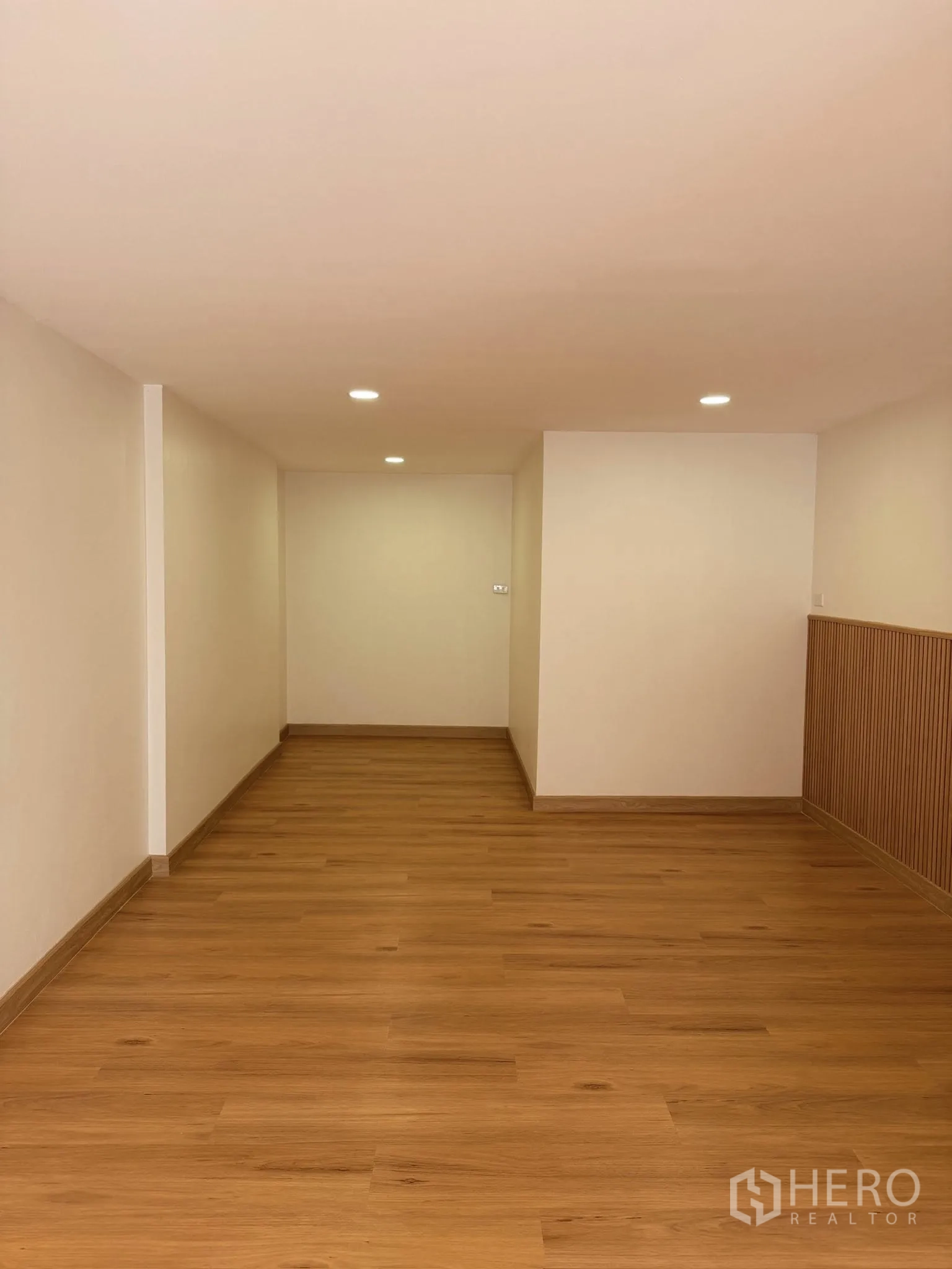 Townhouse for rent or sale in Yan Nawa, Bangkok - Long room with wood-look flooring and slatted feature wall.