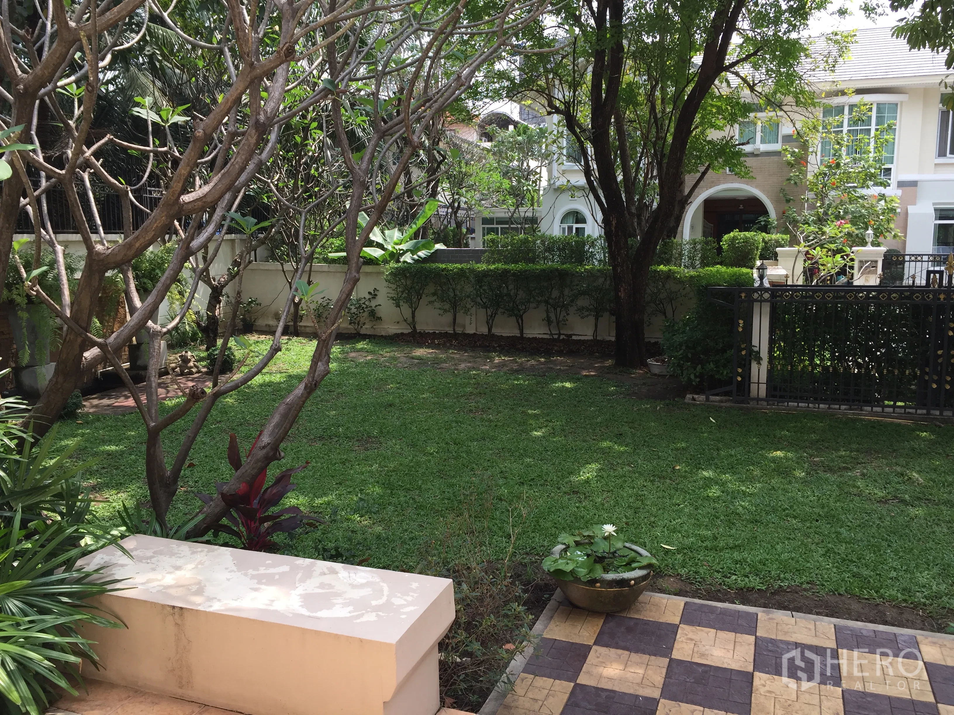 Detached House for rent or sale in Lat Phrao, Bangkok - Private garden with green lawn, mature trees, tiled patio and metal gate.