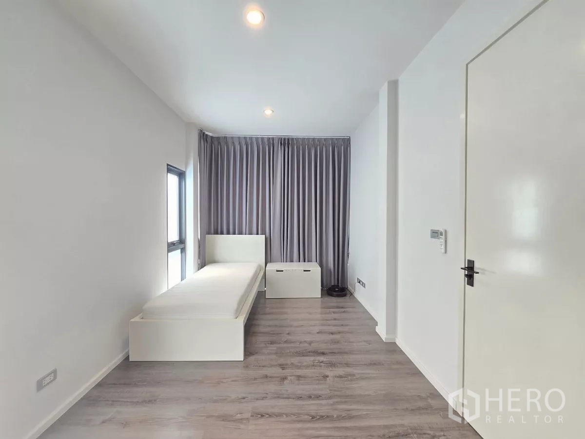 独立式住宅 出租在Prawet, Bangkok - 狭长单人卧室，木地板、落地窗帘与侧窗。