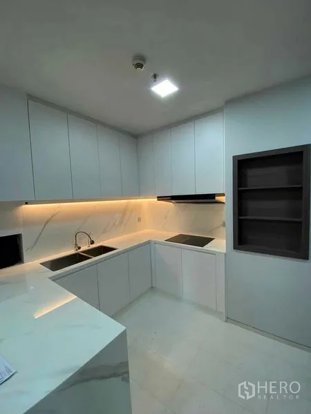Condominium for rent or sale in Khlong Toei, Bangkok - Sleek U-shaped kitchen with dual sinks, induction hob and extensive cabinetry.