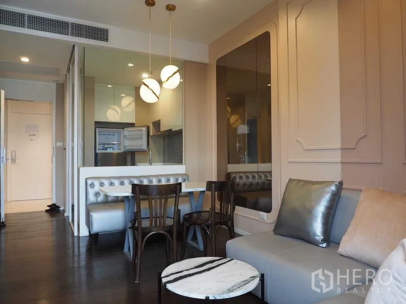Condominium for rent in Chatuchak, Bangkok - Modern living and dining area with tufted banquette, globe pendant lights, mirrored wall and a compact open kitchen.
