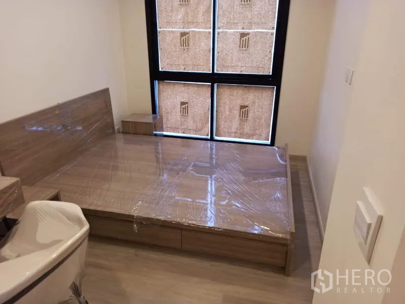 Condominium for sale in Din Daeng, Bangkok - Cozy bedroom with built-in platform bed and a large window with blinds.