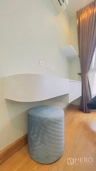 Condominium for rent in Watthana, Bangkok - Floating white desk with blue ottoman beside floor-to-ceiling curtained window.