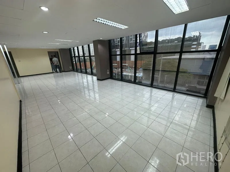 Office Space for rent in Bang Rak, Bangkok - Open-plan office with wide glazed facade and shiny tiled floors looking out to the city.