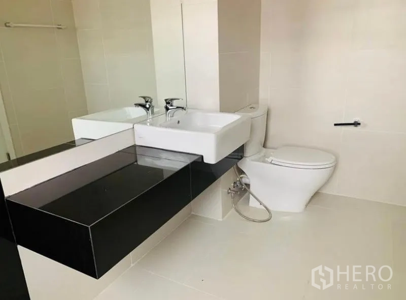 Home Office for rent - Bathroom with long black countertop, square basin, mirror and white tiling.