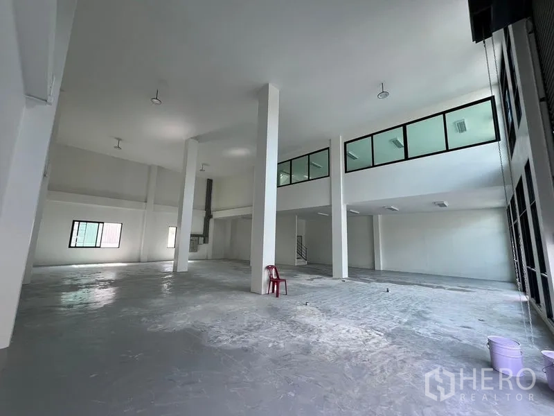 Warehouse for rent in Bang Sao Thong, Samut Prakan - Spacious warehouse hall with high ceilings, mezzanine glass offices and durable concrete flooring.