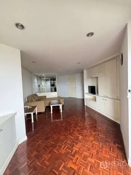 Condominium for rent - Spacious lounge with L-shaped sofa, white cabinetry and glossy wood flooring.