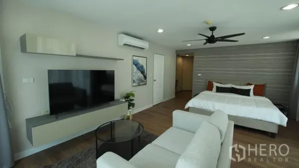 Condominium for rent in Khlong San, Bangkok - Spacious master bedroom with king bed, lounge area, wall-mounted TV, and ceiling fan.