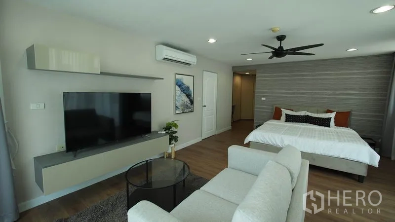 Condominium for rent in Khlong San, Bangkok - Spacious master bedroom with king bed, lounge area, wall-mounted TV, and ceiling fan.